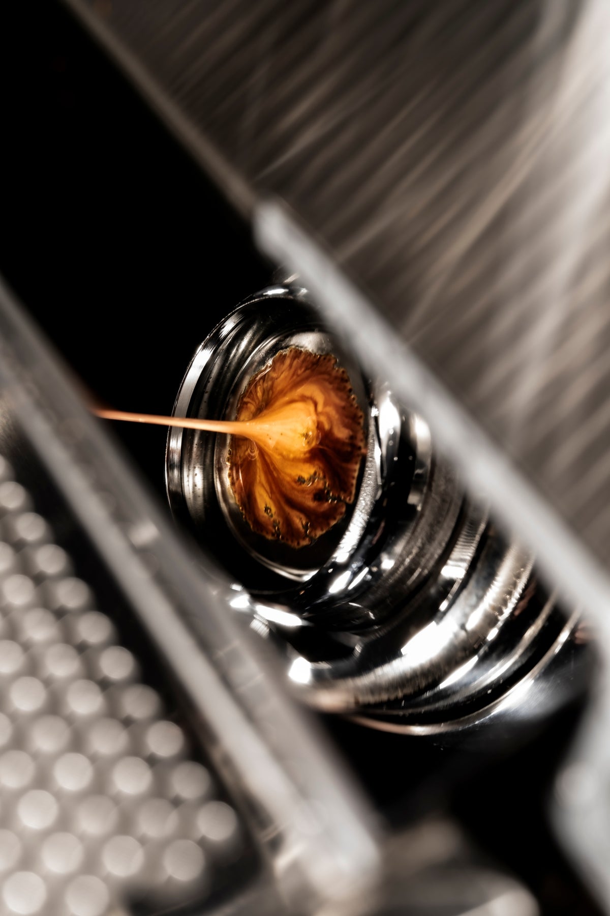 00_06 by Nick Patterson. Espresso flowing from a polished metal portafilter.