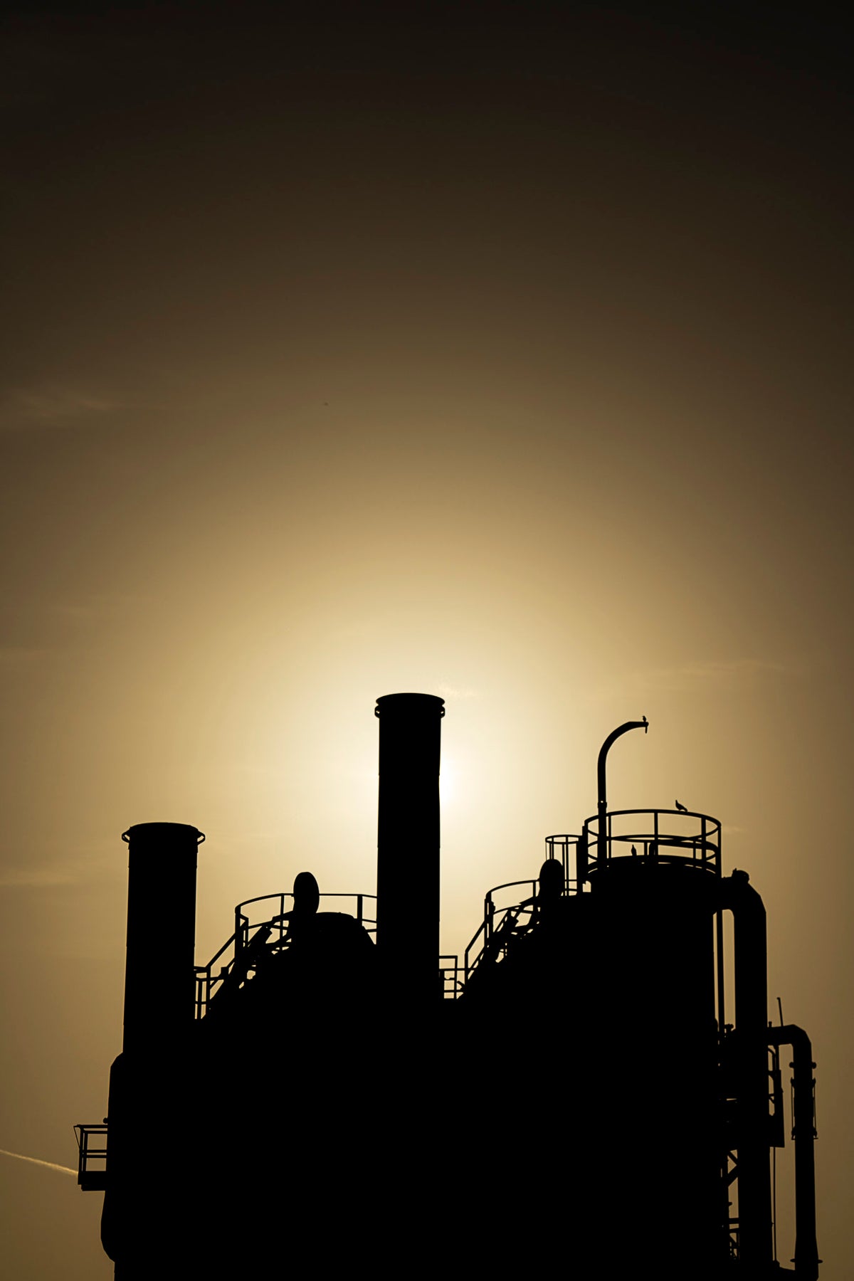 00_36 by Nick Patterson. Industrial structures silhouetted against a warm sky.
