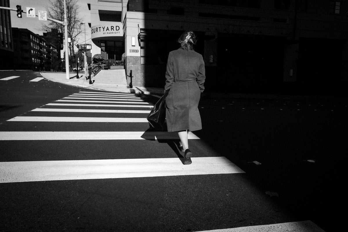 00_05 by Nick Patterson. A person crossing a city street in black and white.