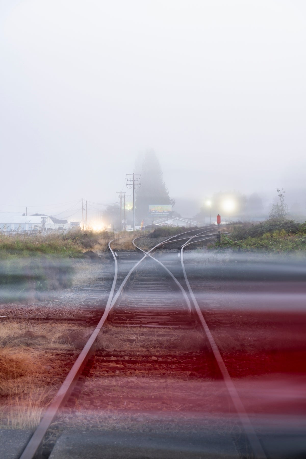 00_11 by Nick Patterson. Railway tracks receding into fog, crossed by a blur of red.