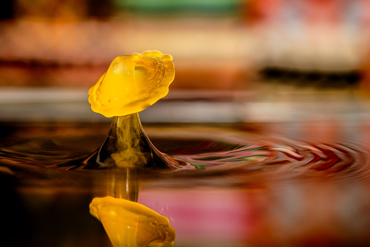 00_08 by Nick Patterson. A rounded yellow liquid splash above a reflective surface.