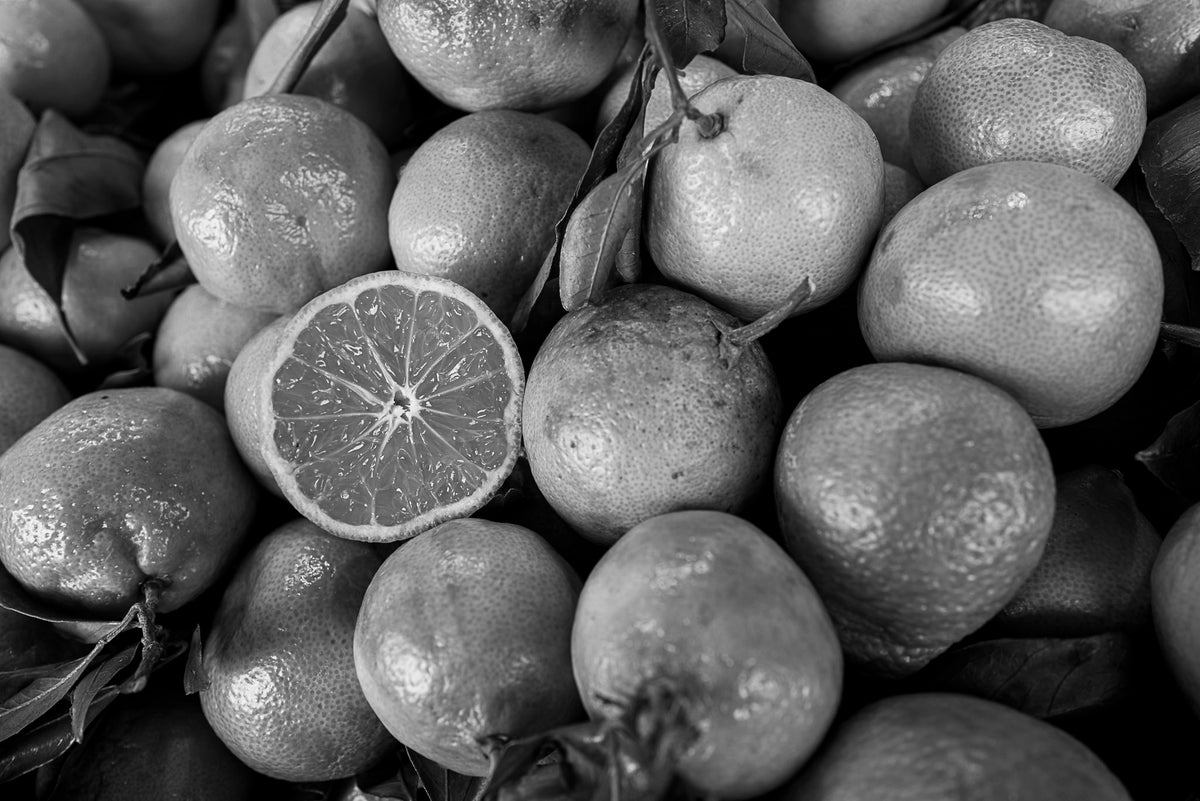 00_37 by Nick Patterson. A pile of citrus fruit with a cut orange in black and white.
