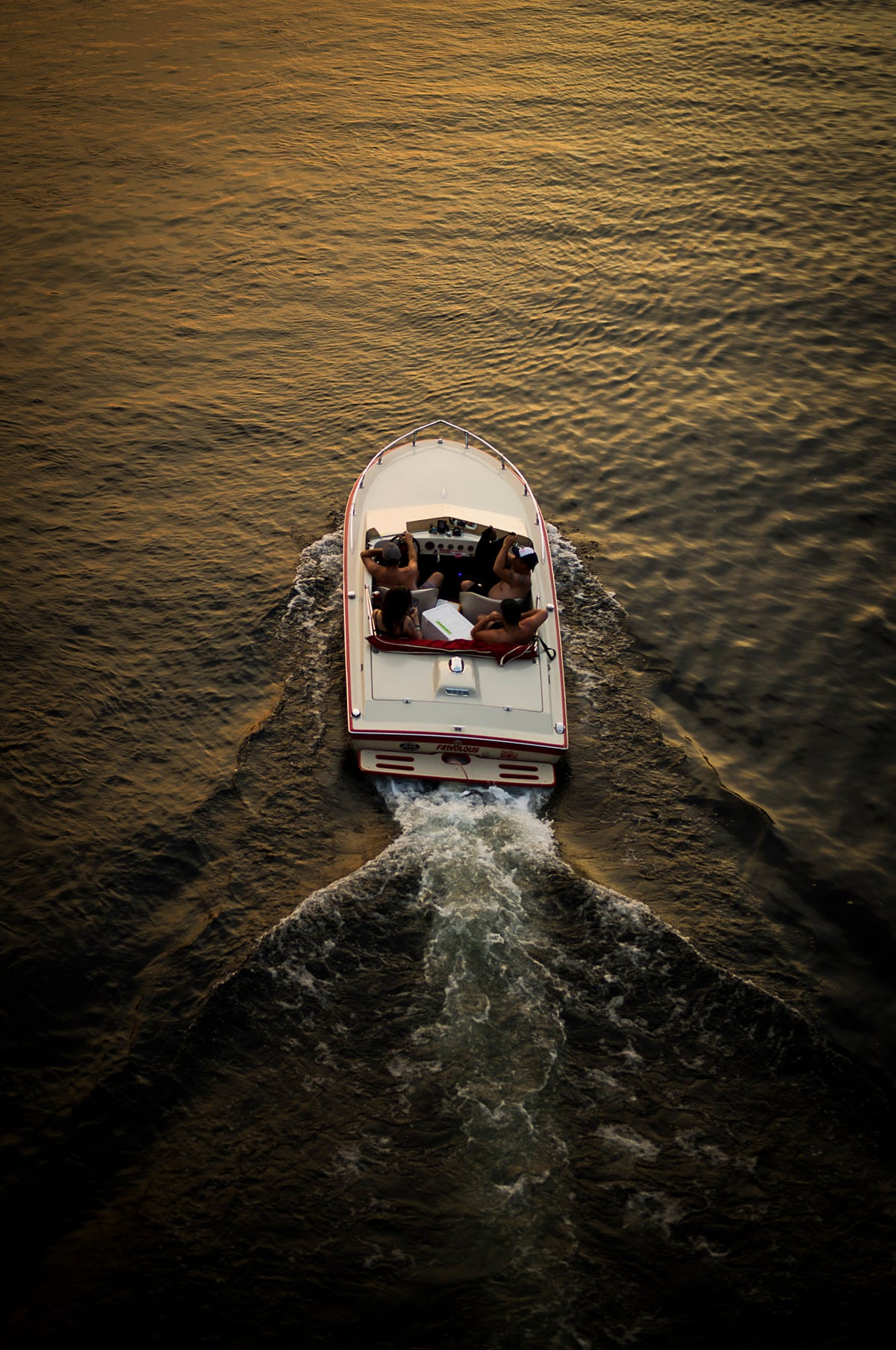 00_24 by Nick Patterson. A small boat leaving a wake across golden water.