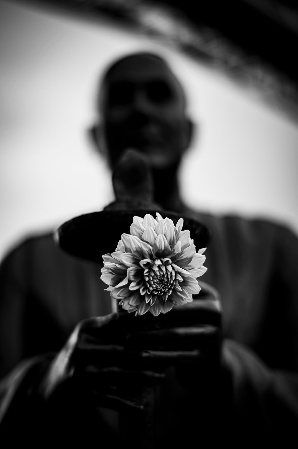 00_26 by Nick Patterson. A person holding a flower toward the camera in black and white.