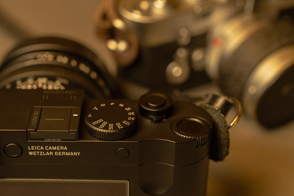Rear and top controls of the Leica Q2 Monochrom with the M3 behind it.