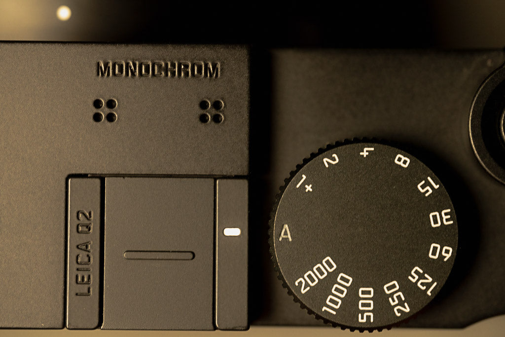 Warm-toned detail of the Leica Q2 Monochrom top plate and shutter-speed dial.