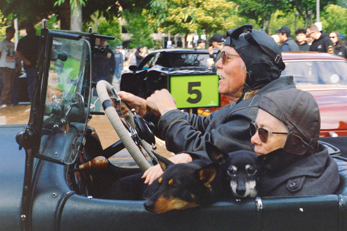 00_21 by Nick Patterson. Two people riding in an open vintage car.