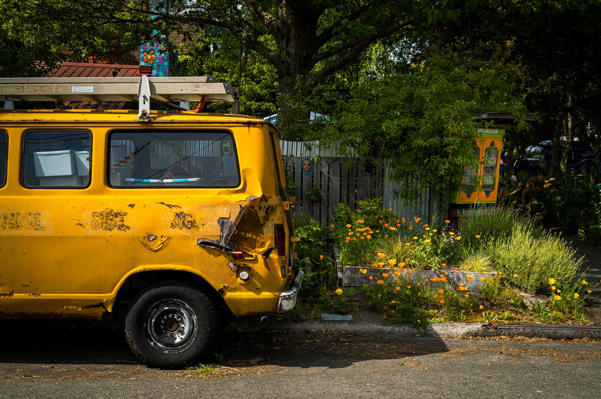 00_03 by Nick Patterson. A yellow van parked beside trees and garden plants.
